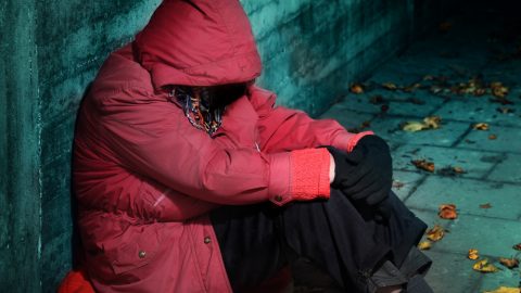 Homeless person wearing red jacket