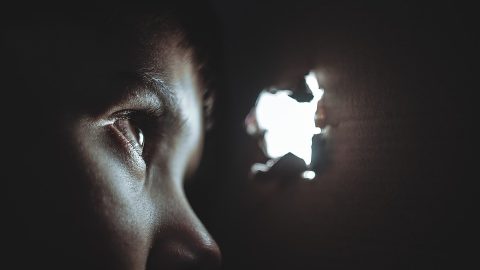 Child hiding peaking through hole