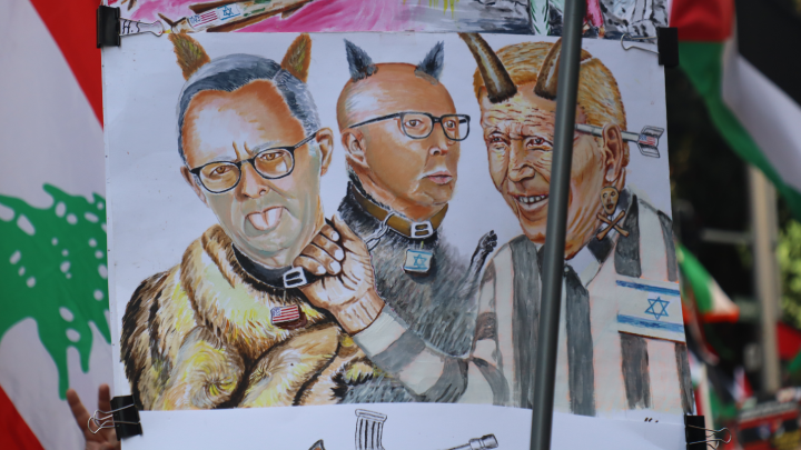 A placard portrayal of US president Joe Biden dominating Australian leaders Anthony Albanese and Peter Dutton