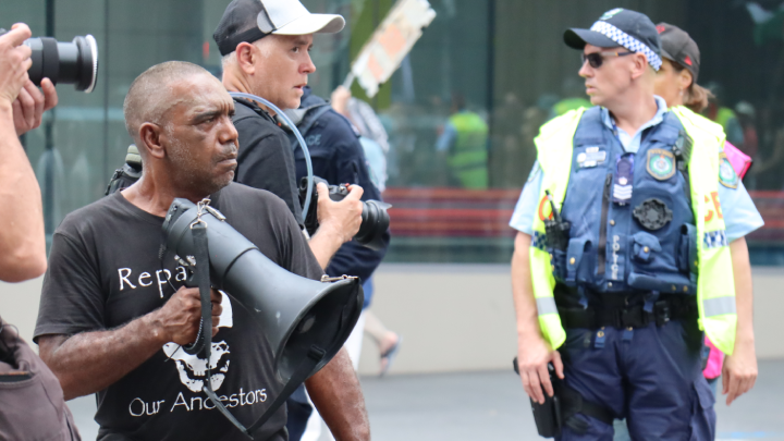 On the megaphone, Gomeroi man Matthew Priestley leads the march in chant at the front of the Sovereignty Day 2025 march on Gadigal land as it made its way up Broadway